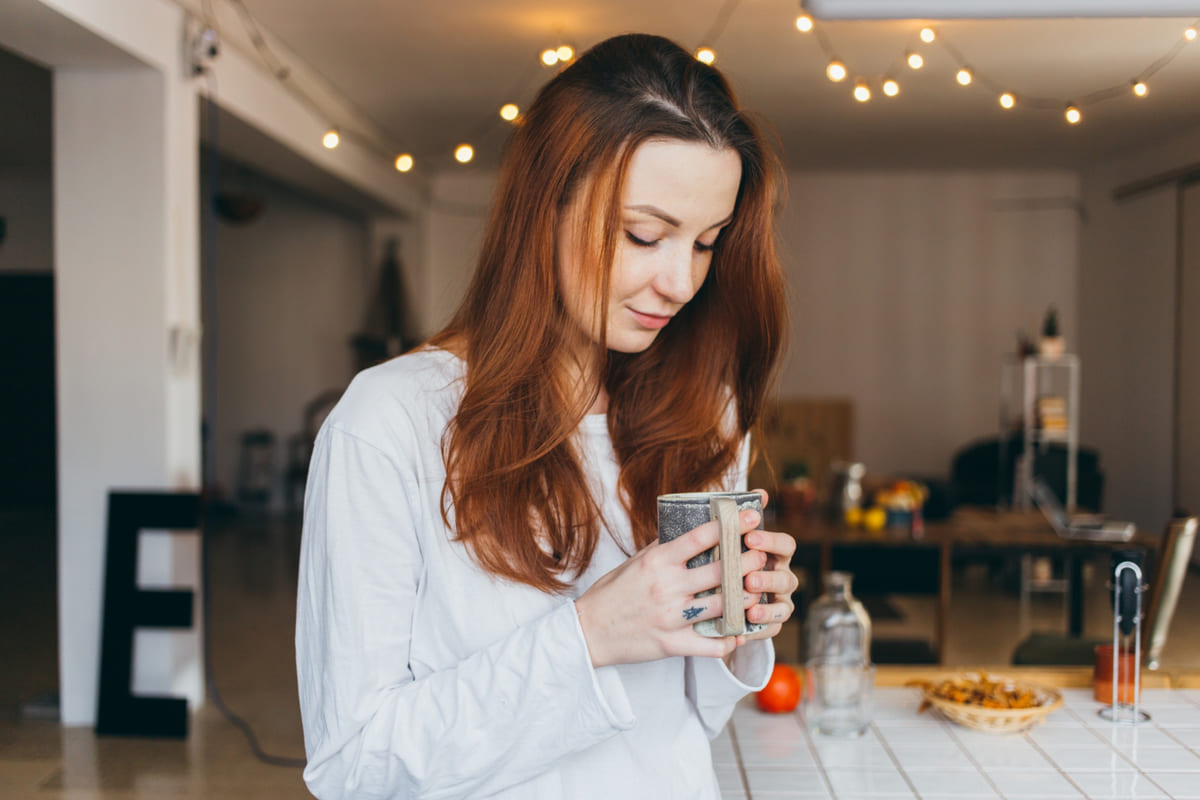 sıcak içeceğini yudumlayan uzun saçlı genç kadın