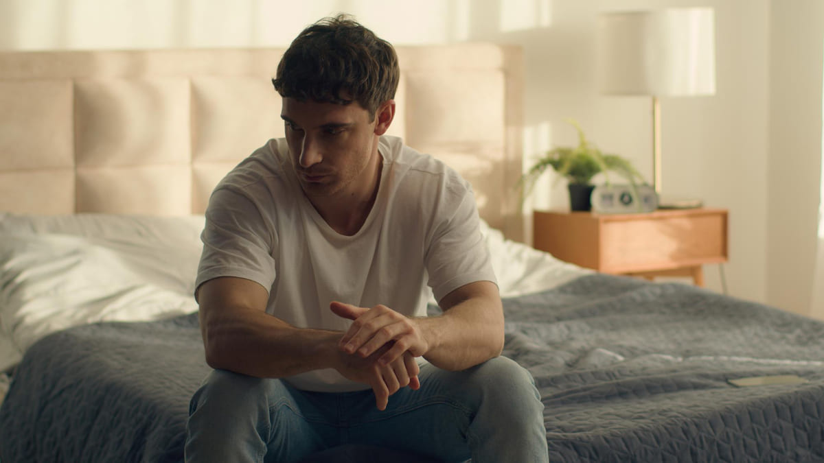 yatak odasında tek başına kapalı bir havada oturan mutsuz genç erkek