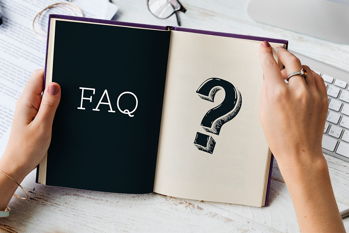 Açık bir defterin sayfalarında büyük bir soru işareti ve "FAQ" yazısı; defteri tutan kadın elleri.