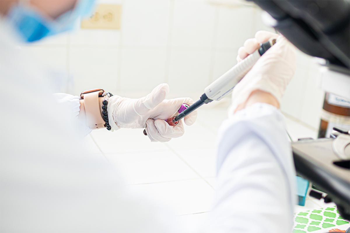 Laboratuvarda, eldivenli uzmanın kan tüpünden otomatik pipetle hassas numune alması.
